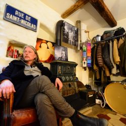 Christophe Calpini en interview durant le Cully Jazz, installé dans un canapé du tHBBC (Cully) sous un panneau de la Rue de Saint-Nicolas. Derrière, une grosse caisse et un porte-manteau. Plusieurs photos de Mehdi Benkler accrochées au mur.